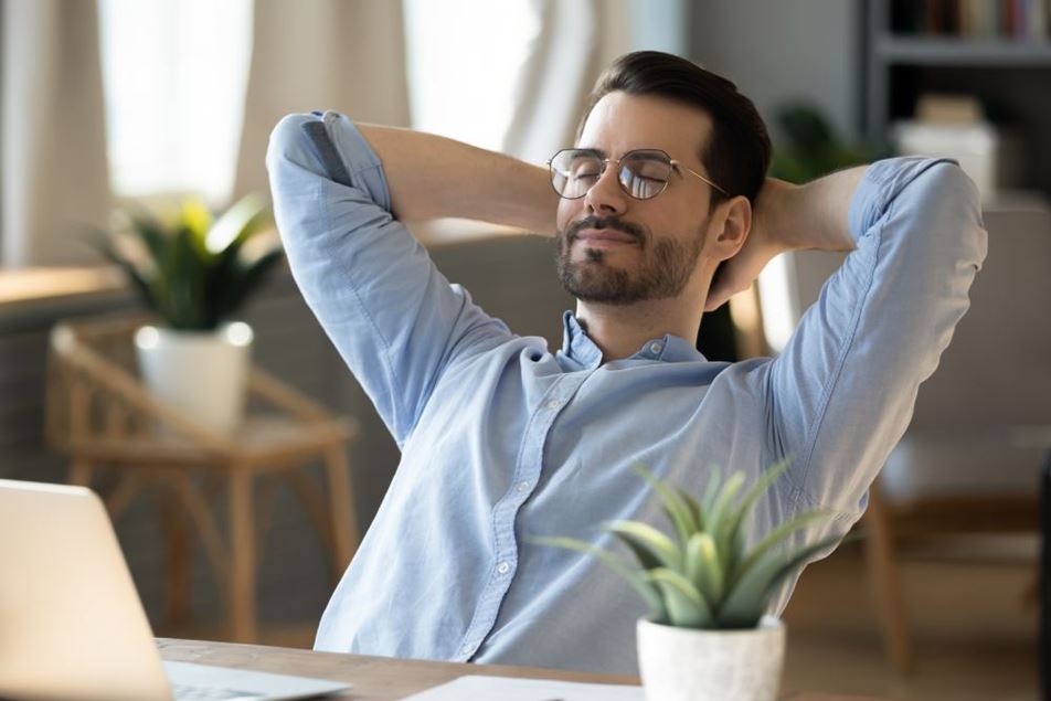 Rustige millennial man in bril zit te ontspannen op het werk op het kantoor thuis, doe een dutje of dagdromen. 
